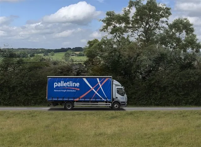 Small Palletline delivery lorry driving along a country road, surrounded by trees and open fields, with bold branding that reads ‘Network Freight Distribution’ on the side.